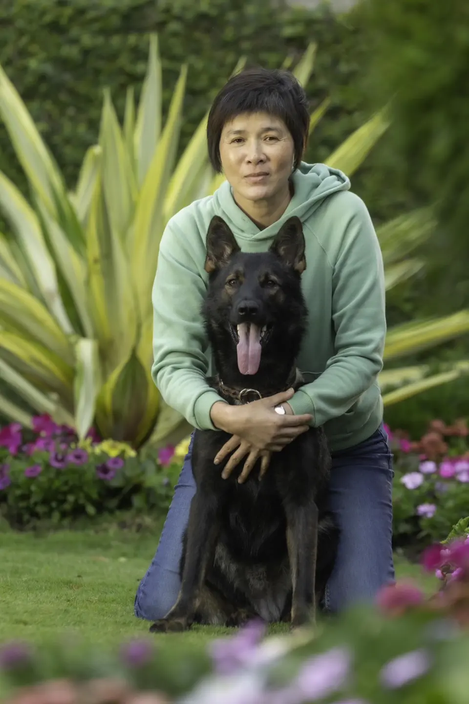 邵秀蘭老師抱著德國狼犬在花園草地